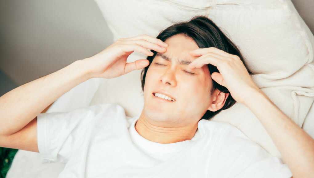 ベッドの上で悩む男