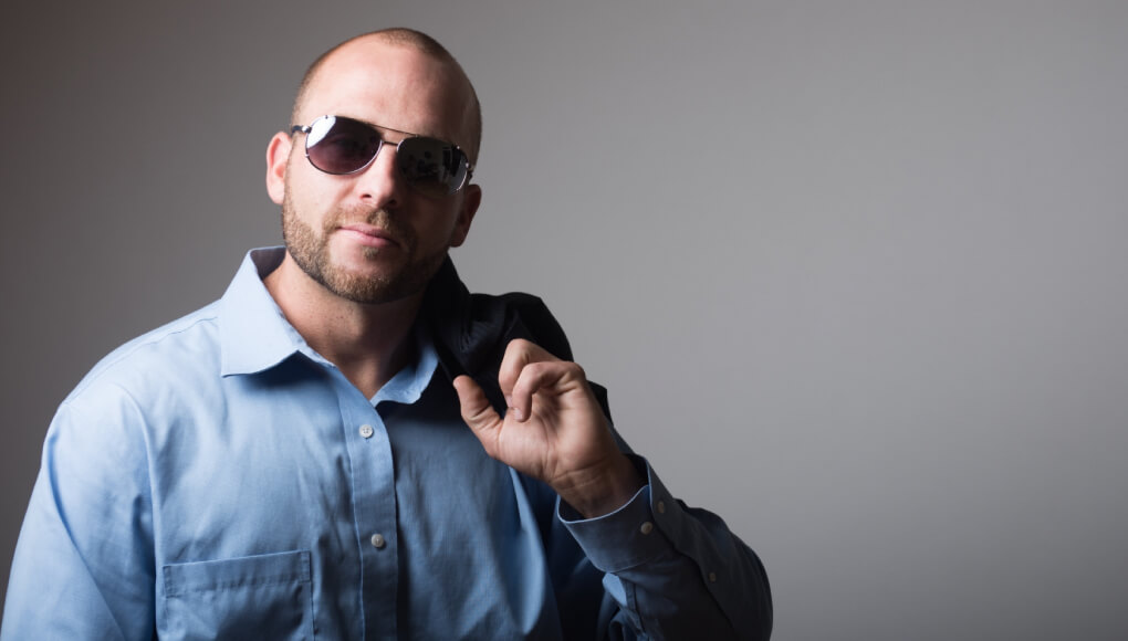 サングラスをかけて青いYシャツを着るスキンヘッドの男性